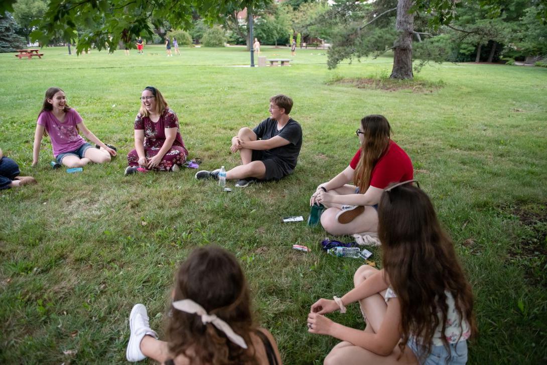 参加荣誉冰淇淋社交活动的学生围成一圈坐在院子里