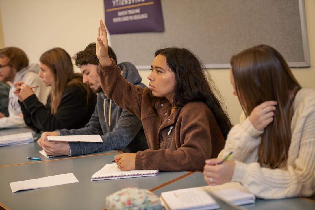 student raising their hand to answer question in psychology class